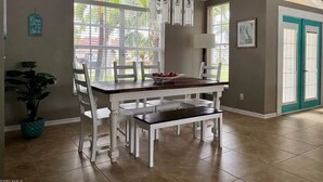 A dining area with a large table, chairs, and hanging light fixtures. - Privacy in Paradise (CapeCoral)