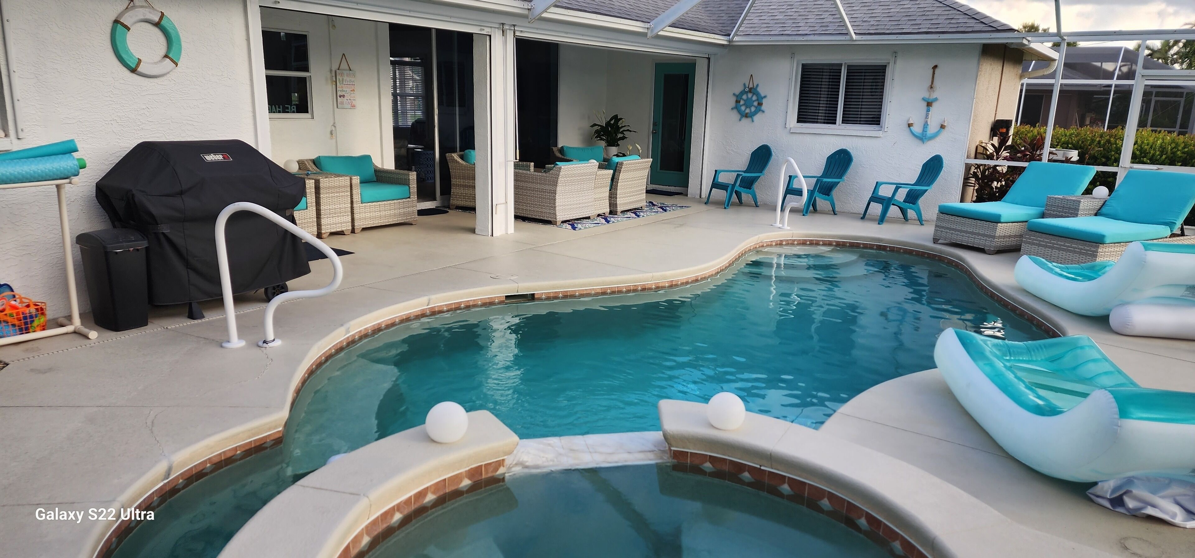 A swimming pool with lounge chairs and a grill area.