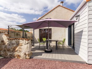 An outdoor patio with a table and chairs, a purple umbrella, and a stone wall. - Country Retreat with Games, Bikes, & Baby Gear Near Nantes and the Sea (Saint-Viaud)