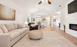 A spacious living room with a sofa, ottoman, and a fireplace.