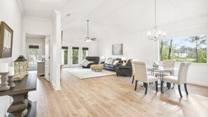 A spacious living room with a large dining table, comfortable seating, and a view of the outdoors.