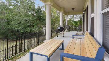 Spacious covered porch with grill, seating, and peaceful wooded views