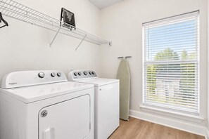 Une buanderie équipée d’un sèche-linge, d’une machine à laver et d’un étendoir à linge.
