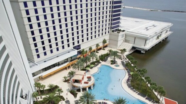 A hotel with a rooftop pool area, multiple swimming pools, and a view of the sea.