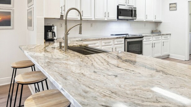 A modern kitchen with white cabinetry, a marble countertop, and a stainless steel sink. - Biloxi Waterfront House With A View / Downtown Biloxi, Ocean Springs & Keesler (Biloxi)