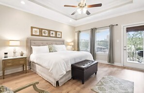 A bedroom with a bed, bedside tables, a ceiling fan, and a view through a sliding glass door. - Bayou Waterfront Cottage with Backyard Fishing (Biloxi)