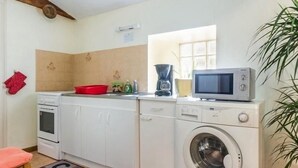 A compact kitchen with a washing machine, microwave, and a red dish rack. - Charming Farmhouse Near Nantes with Pond, WiFi, and Baby Equipment (Corcoué-sur-Logne)