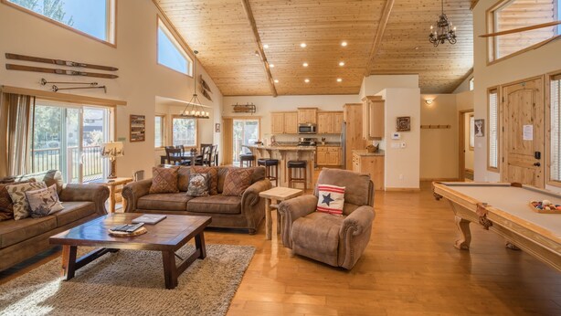 Een ruime woonkamer met een pooltafel, een zithoek en een keuken op de achtergrond.