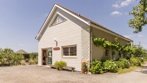 A single-story house with a sloped roof, a front porch, and a small garden area with potted plants and flowers.