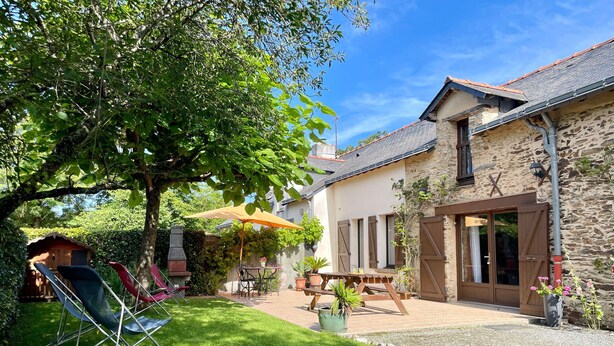 A stone house with a patio, a wooden deck, and a small garden area.