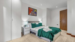 Une chambre à coucher moderne avec un lit, des tables de chevet, un tableau et une porte en bois.