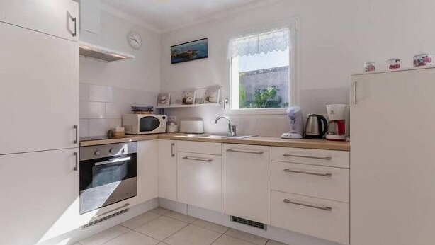 A modern kitchen with white cabinets, a microwave, a kettle, and a coffee maker. - Modern Coastal Home with Garden, Terrace & Parking Near Beaches - Pornic (Pornic)