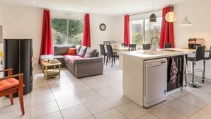 A modern living room with a sofa, dining area, and kitchen island. - Modern House with Garden, Near Nantes - 3 Bedrooms, Wifi, Baby Equipment, Enclosed Garden (Nozay)