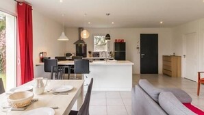 A modern kitchen with a central island, dining area with chairs, and a grey sofa. - Modern House with Garden, Near Nantes - 3 Bedrooms, Wifi, Baby Equipment, Enclosed Garden (Nozay)