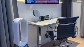 Een moderne kantoorruimte met een grote flatscreen televisie aan de muur, een bureau, een zwarte bureaustoel en een staande speaker.