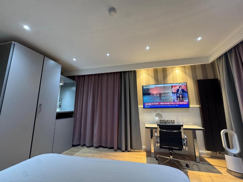 Habitación de hotel con cama, televisor montado en la pared, escritorio con silla y sistema de sonido.