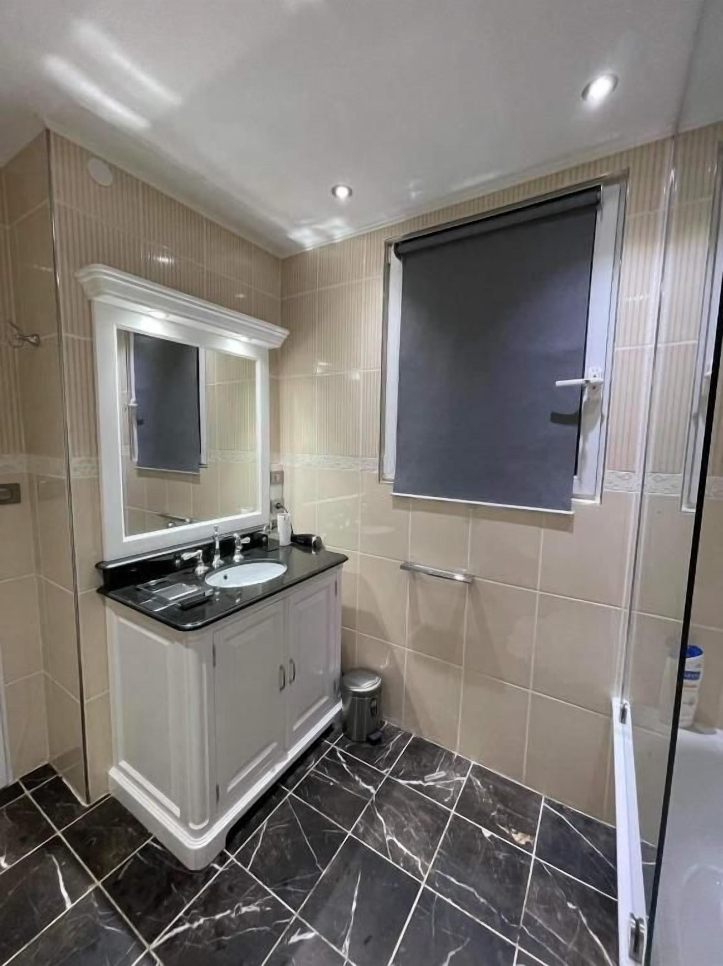Een moderne badkamer met een grote spiegel, een wastafel en een douchehoek.