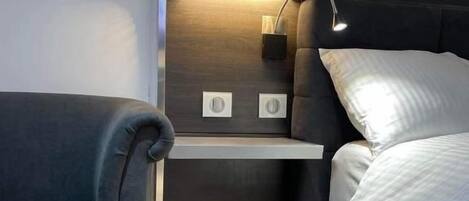 Una habitación compacta con cama, un pequeño rincón de descanso y estantería empotrada.