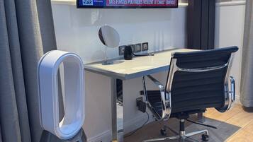 Een moderne kantoorruimte met een groot flatscreentelevisie waarop een nieuwsuitzending draait, een bureau met een stoel en een speaker.