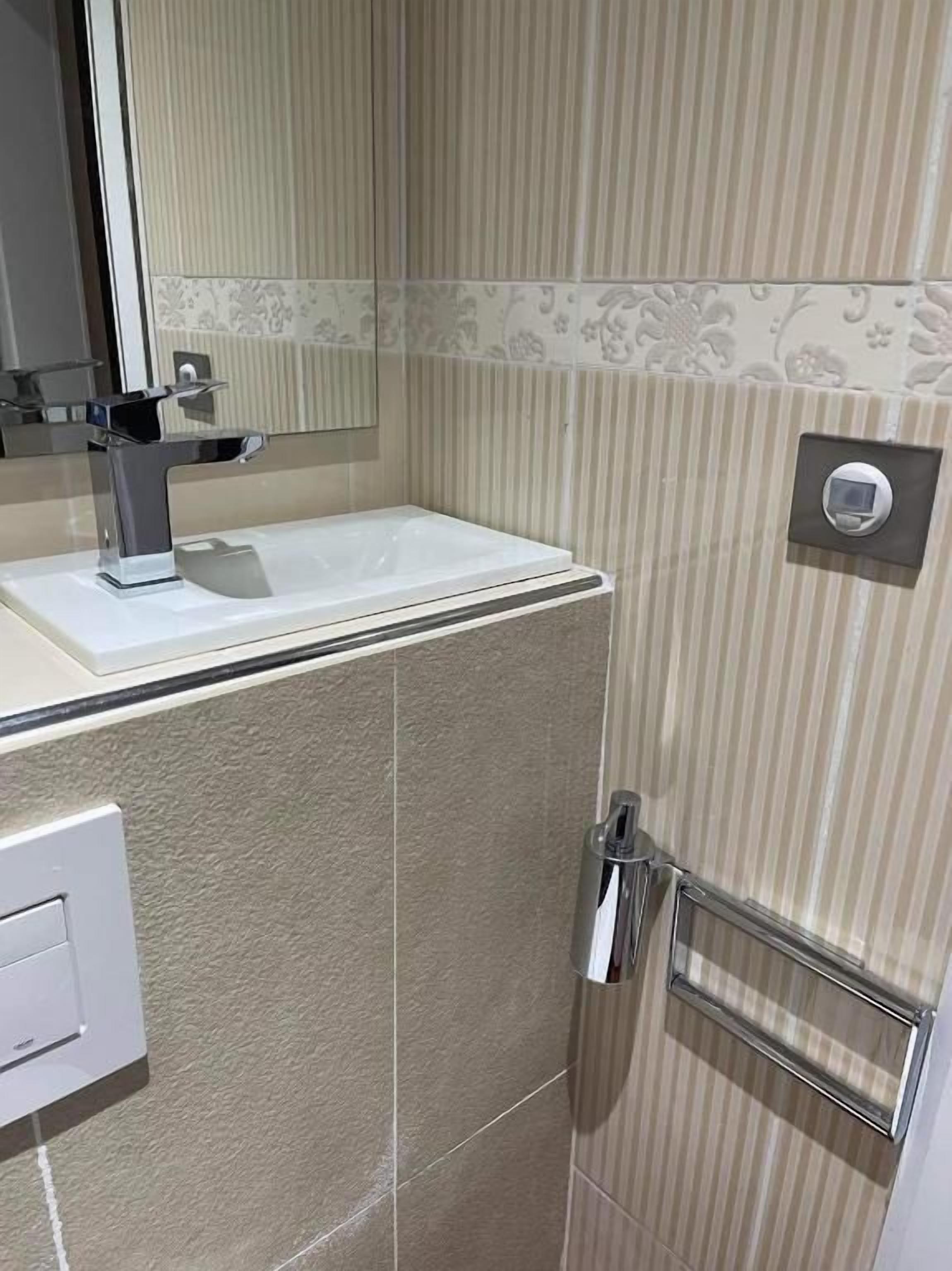 Une salle de bain équipée d’un lavabo, d’un miroir et d’un porte-serviettes.