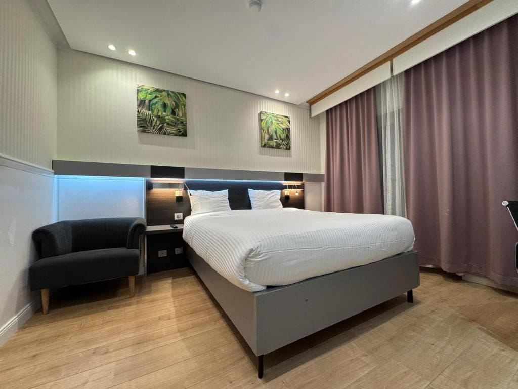Un dormitorio moderno con una cama grande, mesitas de noche, un sofá y obras de arte en las paredes.
