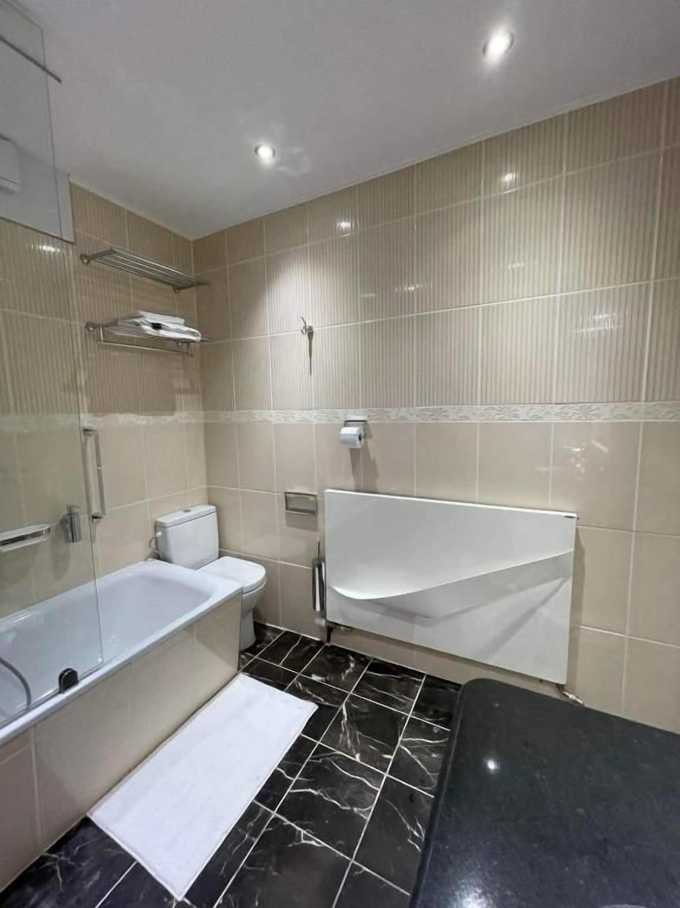 Une salle de bain équipée d’une baignoire, de toilettes et d’une douche séparée par une paroi en verre.