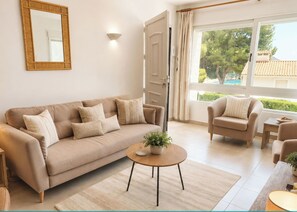 A living room with a beige sofa, a round coffee table, and a chair. - Portina - 3 bedroom villa 5 min from El Portet (Moraira)
