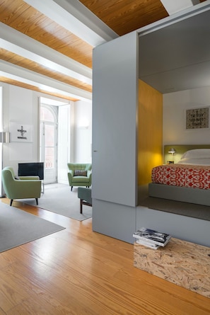 Un dormitorio moderno con una cama, un televisor y un sillón verde.