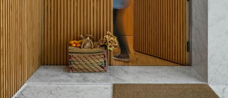 A hallway with wooden panel walls, a marble floor, and a wicker basket with fruits and flowers.