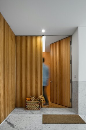 A hallway with wooden panel walls, a marble floor, and a wicker basket with fruits and flowers.