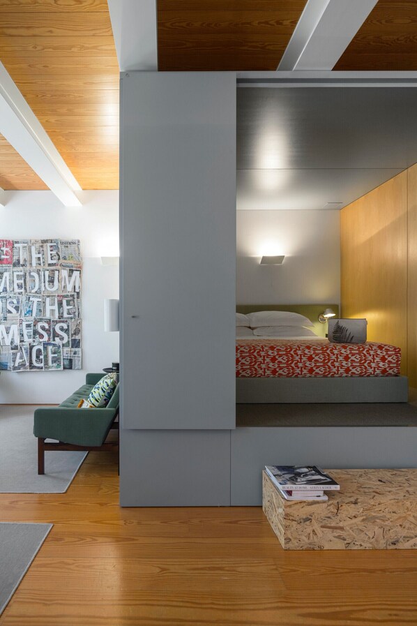A modern bedroom with a built-in bed, a green sofa, and a wall art piece.