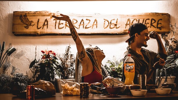 A wooden sign with the text "LA TERAZA DEL ACUER" and a person with a tattoo on their arm. - Aguere Nest Hostel (San Cristóbal de La Laguna)
