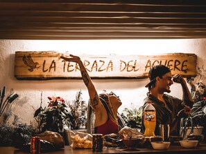 A wooden sign with the text "LA TERAZA DEL ACUER" and a person with a tattoo on their arm.