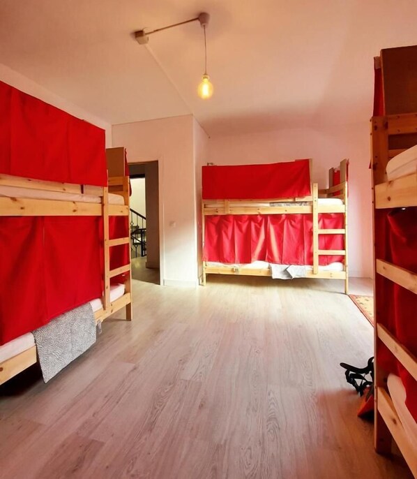 A room with bunk beds, wooden floors, and a hanging light fixture.