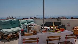 A rooftop terrace with a table set for dining, a sofa, and an umbrella. - Aguere Nest Hostel (San Cristóbal de La Laguna)