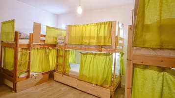 Une pièce avec des lits superposés, un plancher en bois et un luminaire suspendu.