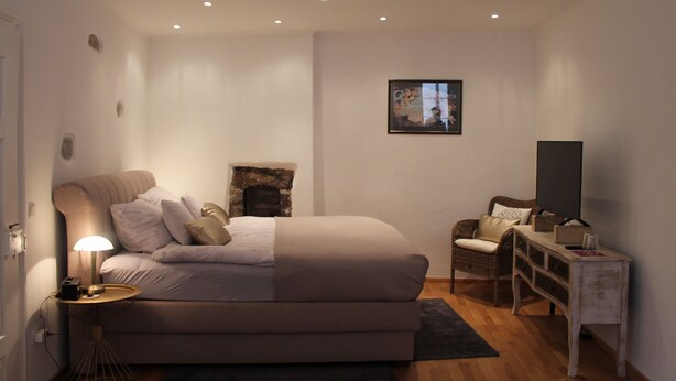 Un dormitorio con cama, mesita de noche, lámpara y televisor.