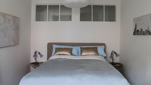 Un dormitorio con una cama grande, una lámpara colgante y dos ventanas.