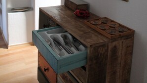Una cocina con armarios de madera, un cuadro en la pared y un estante con adornos.