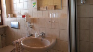 A bathroom with a sink, mirror, towel rack, and a hand dryer. - Pension Zum Schwan (Muhr am See)