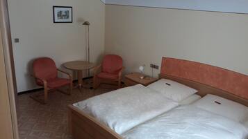 Ein Hotelzimmer mit einem Bett, zwei Stühlen, einem kleinen Tisch, einer Lampe und einem Bild an der Wand.