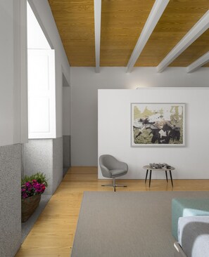 A modern living room with a grey armchair, a small round table, and a framed artwork on the wall. - Flattered to be in Porto Sea View Apartment A (Oporto)