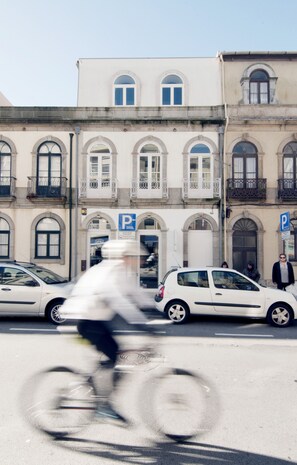 A street scene with a building featuring multiple windows and balconies, a parking sign, and a white car parked in front. - Flattered to be in Porto Sea View Apartment A (Oporto)