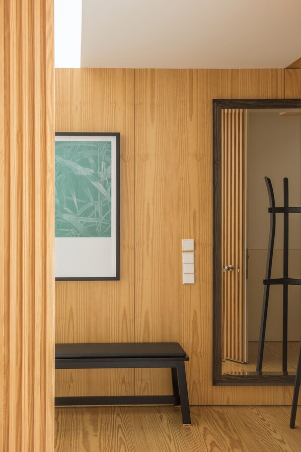 Een houten wand met een lijstfoto, een bank, een deur met spiegel en een lichtschakelaar.