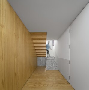 A modern interior with a wooden wall, a marble staircase, and a person walking. - Flattered to be in Porto Sea View Apartment A (Oporto)