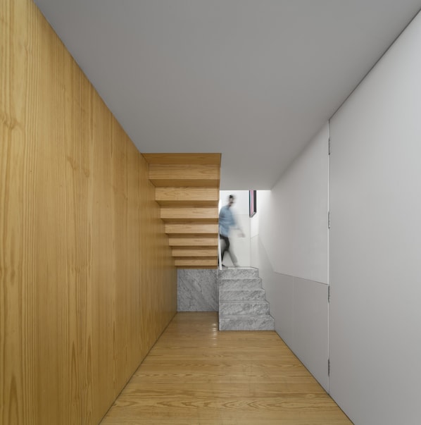 A modern interior with a wooden wall, a marble staircase, and a person walking. - Flattered to be in Porto Sea View Apartment A (Oporto)