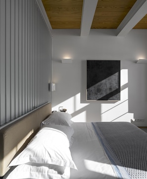 A modern bedroom with a large bed, a wooden ceiling, and a wall-mounted artwork. - Flattered to be in Porto Sea View Apartment A (Oporto)