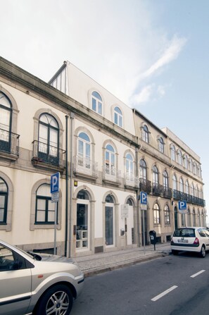 A multi-story building with a classic architectural style, featuring arched windows and balconies. There are multiple parking signs indicating available parking spaces.