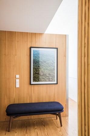 A wooden wall with a framed picture, a bench, and a light switch. - Flattered to be in Porto Sea View Apartment A (Oporto)