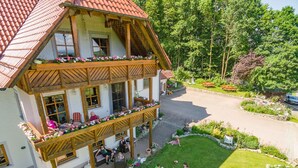 A two-story building with a balcony, a paved courtyard, and surrounding greenery. - Eulenberghof Kraus (Altenkunstadt)